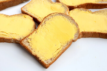 Bread slices with butter on white background.