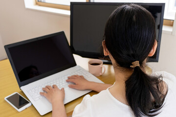 自宅のテーブルでパソコン作業をする女性のイメージ