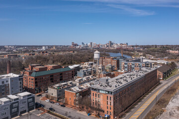 Fototapeta na wymiar Aerial panorama view of Rocketts Landing near Richmond Virginia, regentrified industrial shopping complex with luxury apartments in former warehouses, water tower along the James river with blue sky