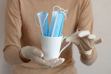 Two hands in white gloves holding a ceramic cup with blue masks