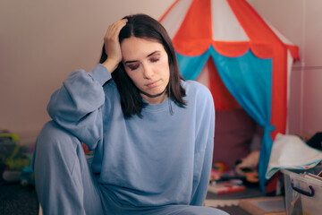 Exhausted Mother Sitting on the Floor Surrounded by Toys