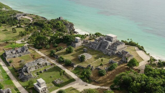 Drone video of the Mayan pyramids. Ancient buildings with temples stand on a rock by the sea in a beautiful landscape in the historic city of Tulum. Aerial view Cancun Mexico.