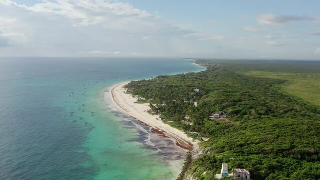 Drone video of the Caribbean coastline. A line of the sea on the shore of which are sandy beaches and impassable jungle in a landscape with clear water and waves. Aerial view Mexico.