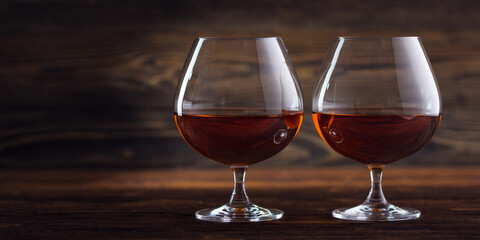 Glass of cognac, brandy or whiskey on natural wooden background. Classic cognac glass. Alcohol...
