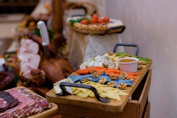 Serving wooden desk with various cheeses on the party on the meat food background.