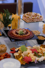 Front view of serving table with a variety of sliced meat and other food on the banquet table.