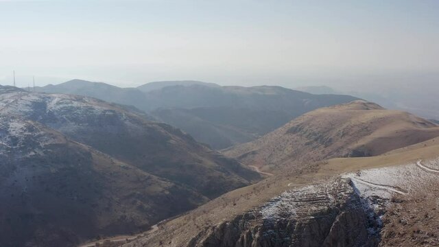 Drone video of a mountain landscape in early winter. Mountain ranges and peaks are sprinkled with snow. Rocky sand mountains in the Middle East. 