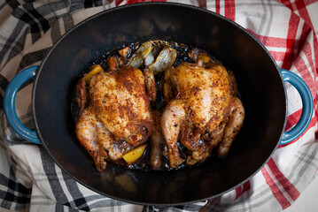 Cornish Hens fresh out of the oven in a blue cast iron roasting dish
