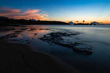 .Long exposure scene of Hoshizuna beach after sunset. Colorful clouds reflecting in the water. Rock platform mixing with moist sands, smooth surface sea bringing calm and tranquility to the view.