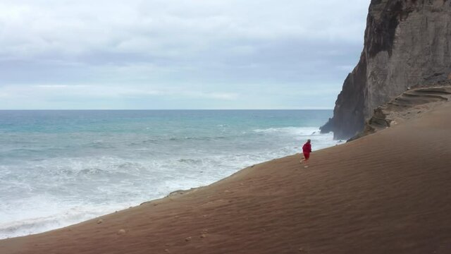 Panoramic shot of man running on coast of at atlantic ocean on Faial Island, Azores, Portugal, Europe. Aerial view of sporty guy training at Capelinhos Volcano, 4k footage