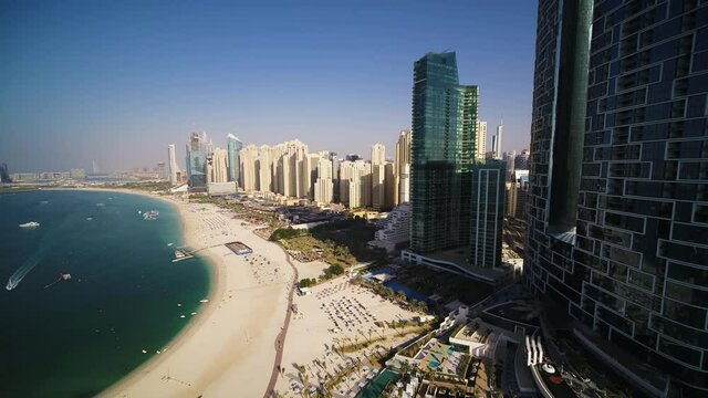 Aerial view of a beautiful beach with golden sand facing the Persian gulf with Dubai tall skyscrapers skyline in background, Dubai, United Arab Emirates.
