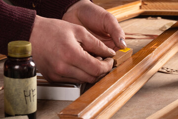 door restoration, the master selects the color of the wax to repair scratches and chips on an old wooden door