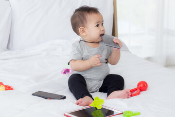 Portrait of cute little baby girl sitting with cozy on bed at bedroom, happiness of toddler, newborn 6-11 months with innocence and expression with cheerful, child charm, indoors, one person.