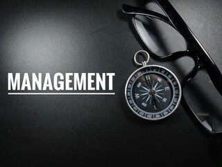 Business concept.Text MANAGEMENT with glasses and compass on black background.