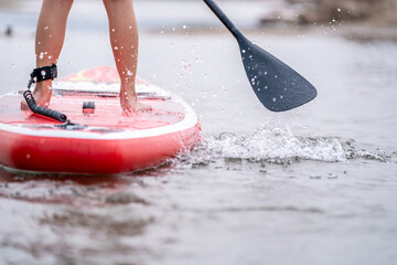 close-up of legs Stand up paddle boarding on the river. - obrazy, fototapety, plakaty