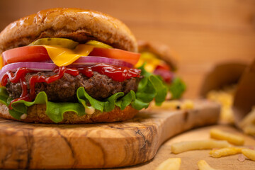 Hamburger or burger on a background with fries on a wood background