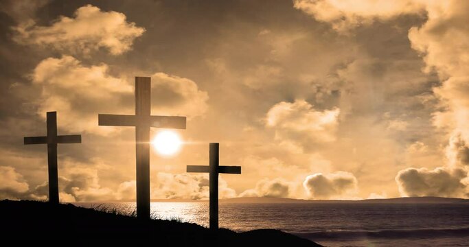 Animation of three christian crosses over landscape with sun glowing on orange sky