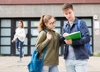 Two students discuss past lessons at a college on the street