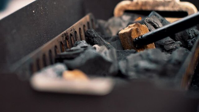 Lighting a firestarter between the charcoal in a small grill