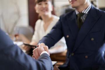 握手をするアジア人ビジネスマンの手元 © mapo