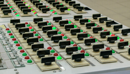 Obraz premium Control panel with rows of rotary switches and green and red lamps. Concept - production , power station. Selective focus.