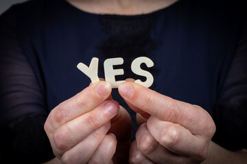 YES. Word from white letters of wooden alphabet in woman's hand