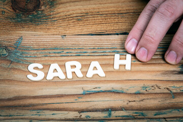 SARAH. Name of women and girls. White letters of the alphabet on a wooden background