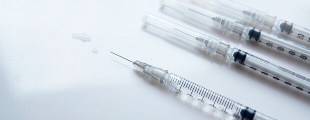 Closeup banner disposable syringes with needle for medical purpose and COVID-19 white table background at clinic or hospital with copy or negative space. Healthcare and vaccination concept