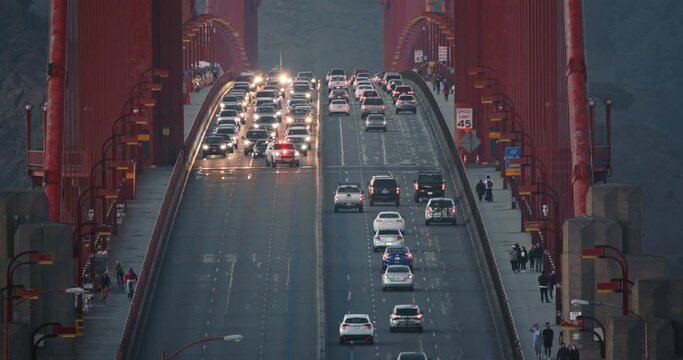 San Francisco, October 2020. Transportation on world famous bridge. Police car with flashing lights is stopping vehicles. Evening traffic on Gold Gate Bridge in sunset light