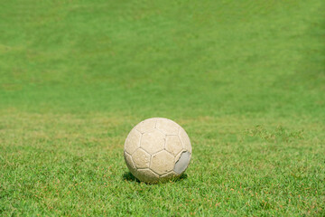 Fototapeta na wymiar Old soccer ball on green grass of soccer field.
