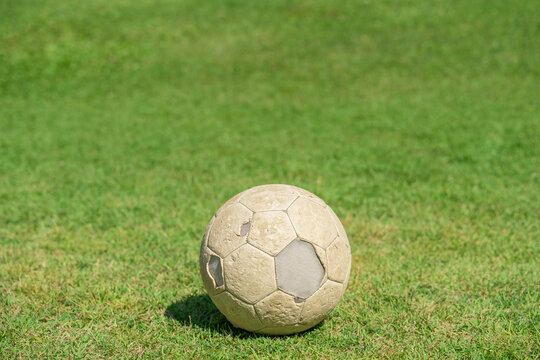 Old soccer ball on green grass of soccer field.