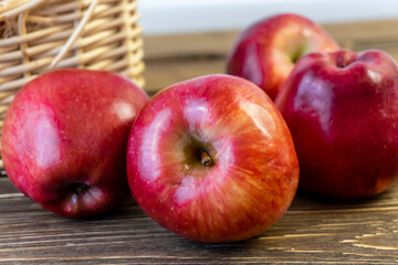 Red apples in a basket and on a wooden table