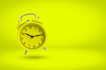 Yellow alarm clock isolated on yellow background with copy space.