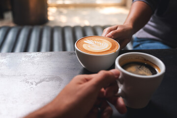 Closeup image of a man and a woman holding white coffee mugs in cafe