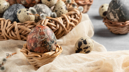 Easter composition - several marble eggs painted with natural dyes in a wicker nest and baskets