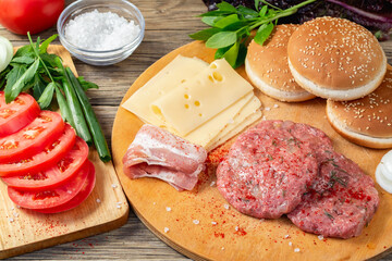 Process of cooking homemade burgers, meatballs, tomatoes, cheese and other ingredients on a wooden table, flat lay, top view