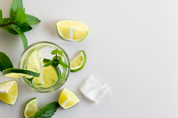 Fresh homemade cocktail with lime, mint and ice on a white table, close up, top view, copy space