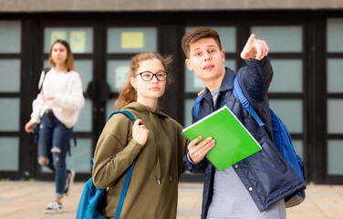 Young man prompts the girl, pointing with his hand at something. High quality photo