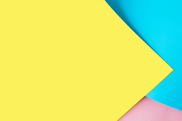 Multicolored sheets of paper placed geometrically randomly. Yellow, pink, blue
