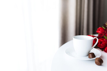 Bouquet of red tulips on table and white coffee cup. Concept for greeting card