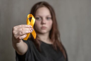 Teen girl holds yellow ribbon. Concept of suicide problems and their prevention