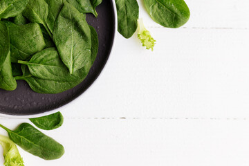 Bowl with fresh green salad leaves, spinach, lettuce, basil on white background
