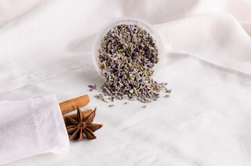 Ingredients to make tea. Cinnamon, badyan, green tea with herbs, dried lavender. Light fabric background, imitation of folds.