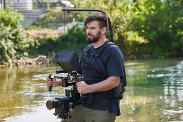 a professionally equipped cameraman shoots in the water surrounded by beautiful nature.