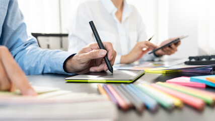 graphic designer team working on web design using color swatches editing artwork using tablet and a...
