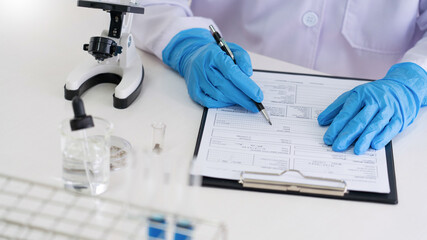 scientists researching in laboratory in white lab coat, gloves analysing, looking at test tubes sample, biotechnology concept