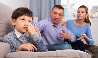 Fototapeta na wymiar Portrait of offended boy after quarrel with parents sitting on sofa at home. High quality photo