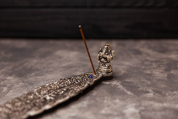 Aromatic religious stick in a metal stand on a grey background. Incense sticks smoldering on table in room. Space for text. Dry fragrant soothing stick. Concept of zen, meditation. Subject of rituals.