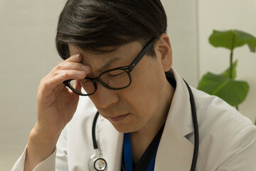 疲れている目を押さえている医師