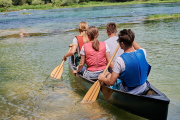 Group adventurous explorer friends are canoeing in a wild river